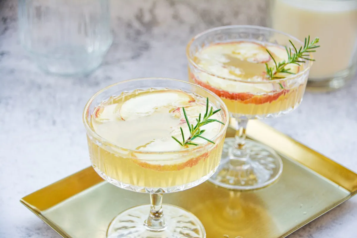 Bol de soupe crème couleur beige, parsemé de persil ciselé et de copeaux de champignons, posé sur une nappe en lin avec une cuillère en bois