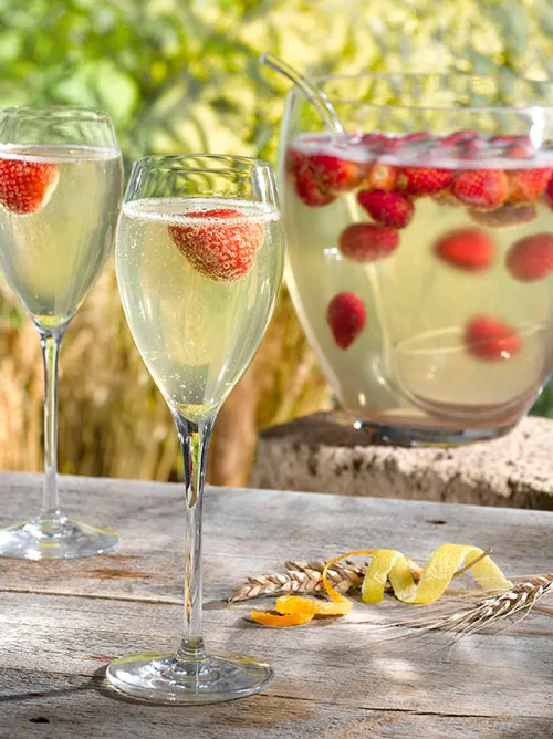 Bol blanc de soupe mousseuse avec une cuillère en argent et des fines herbes, flacon de champagne en arrière-plan